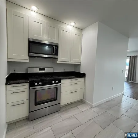 a kitchen with granite countertop cabinets stainless steel appliances and a counter space