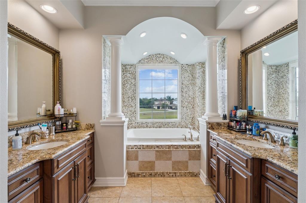 1172 Castle Pines Court Reunion, FL 34747 - Photo 32 of 65 a bathroom with a granite countertop double vanity sink a mirror and a bathtub