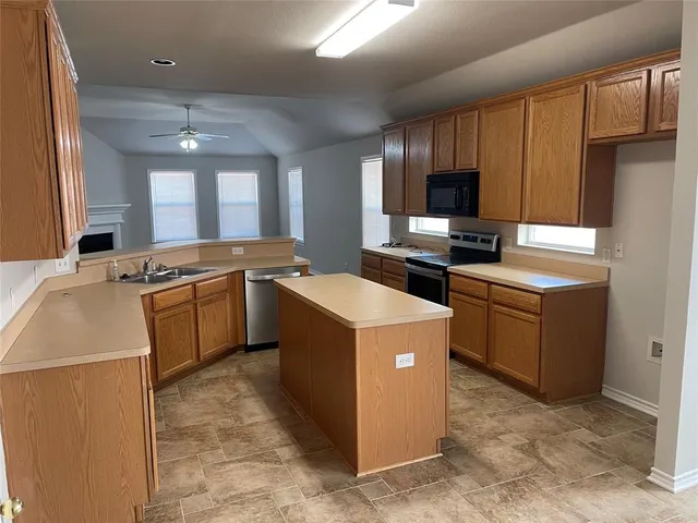 a kitchen that has a sink a stove top oven a refrigerator cabinets and a counter top space