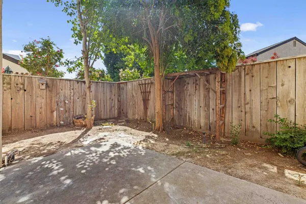 a backyard of a house with plants and trees with wooden fence