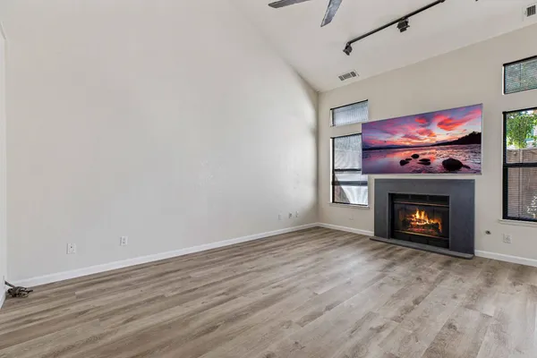 a view of an empty room with wooden floor fireplace and a window