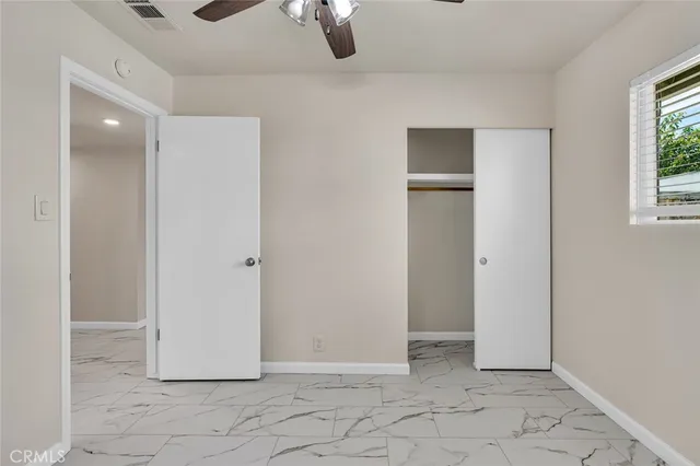 a view of an empty room with window and cabinet area