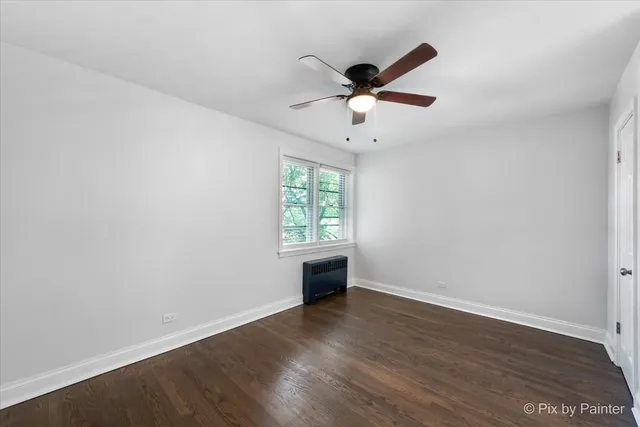 an empty room with wooden floor ceiling fan and window