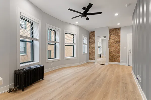 a view of an empty room with a window and wooden floor