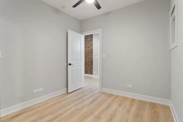 an empty room with wooden floor chandelier fan and windows