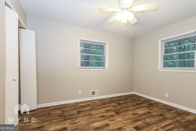 a view of empty room with wooden floor and fan