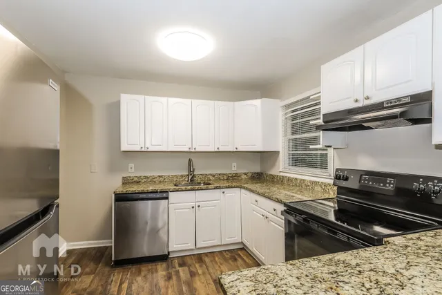 a kitchen with granite countertop a sink a stove and cabinets