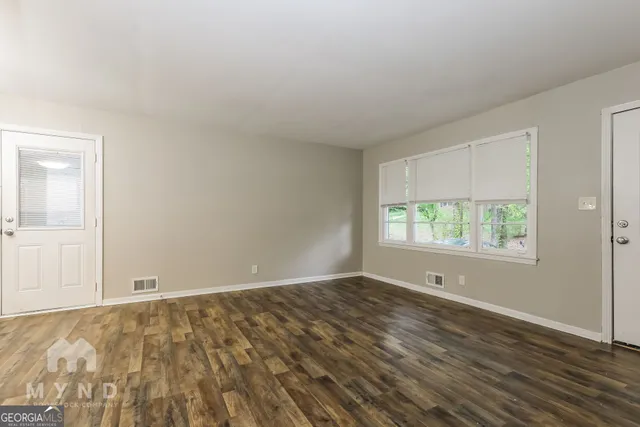 an empty room with wooden floor and windows