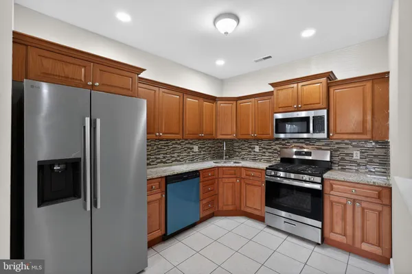 a kitchen with stainless steel appliances granite countertop a refrigerator and a stove top oven