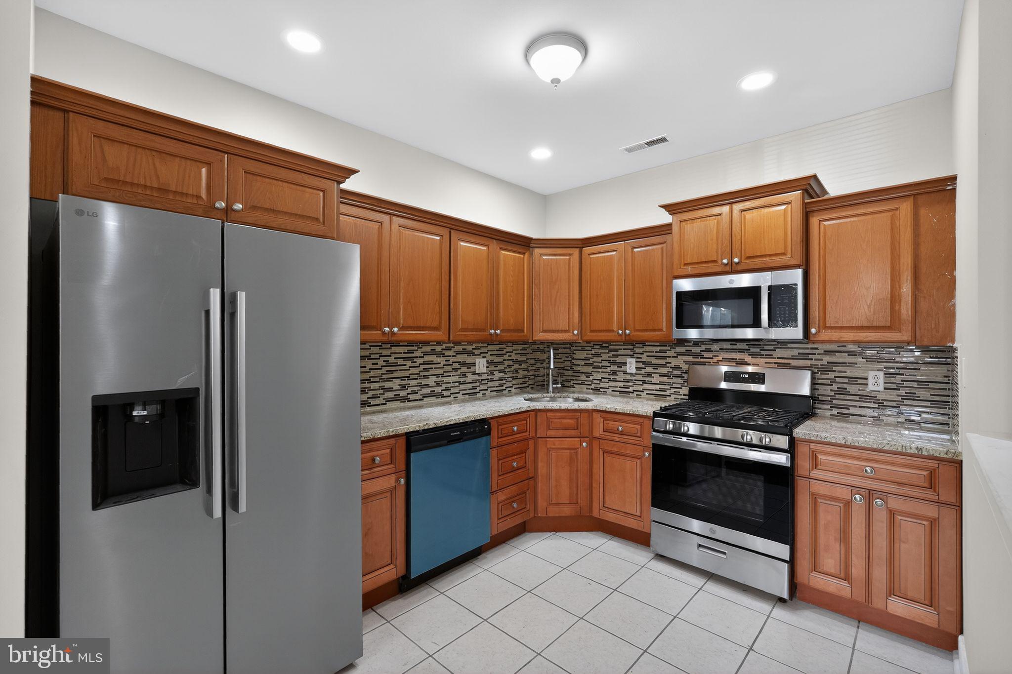 a kitchen with stainless steel appliances granite countertop a refrigerator and a stove top oven