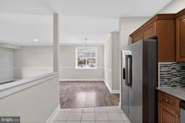 a view of a refrigerator in kitchen and an empty room in wooden floor