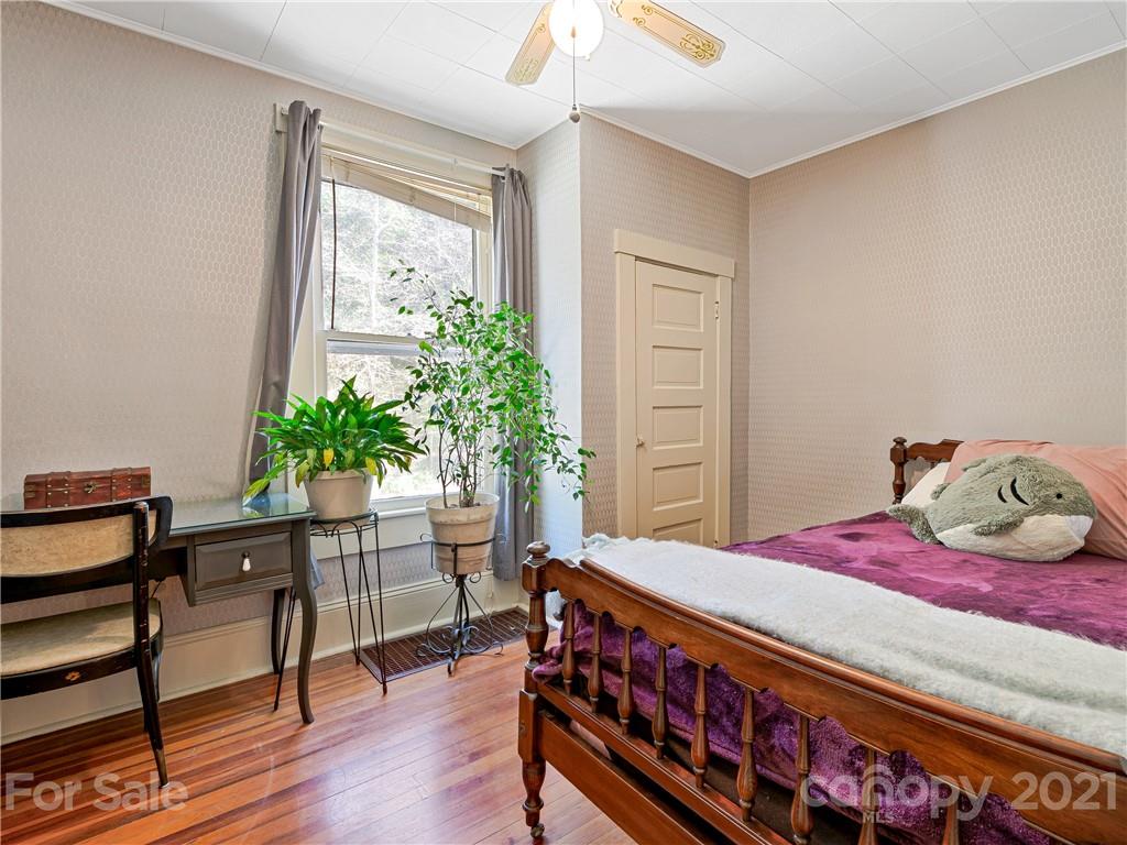 604 Fairview Road Asheville, NC 28803 - Photo 5 of 18 a bedroom with a bed table and a window
