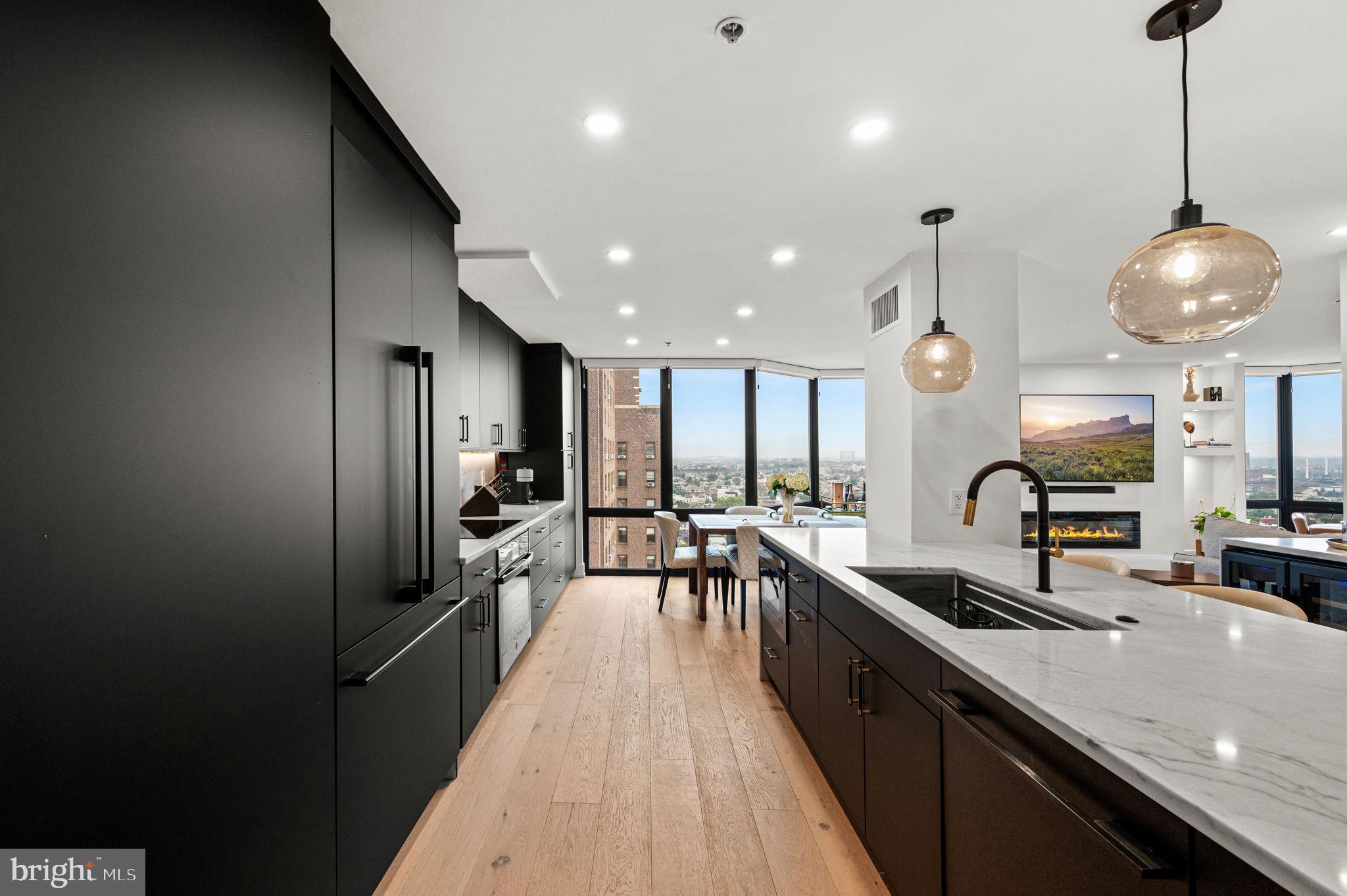 2020 Walnut Street, Unit 19LM Philadelphia, PA 19103 - Photo 5 of 60 a large kitchen with stainless steel appliances a large counter top a stove a chimney a sink and a refrigerator