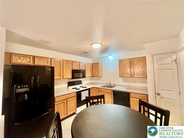 a kitchen with stainless steel appliances a refrigerator a stove a sink a dining table and chairs