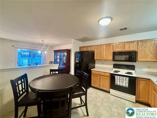 a kitchen with a dining table chairs and refrigerator