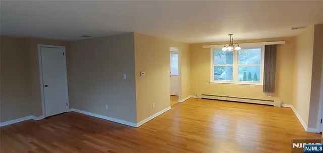 a view of an empty room with window and wooden floor