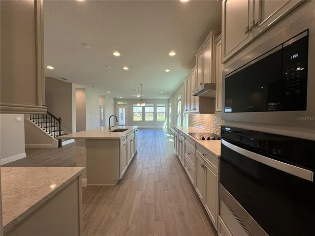 a large kitchen with stainless steel appliances granite countertop a large stove a sink dishwasher and a microwave oven with wooden floor