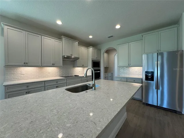 a kitchen with granite countertop a refrigerator and a sink