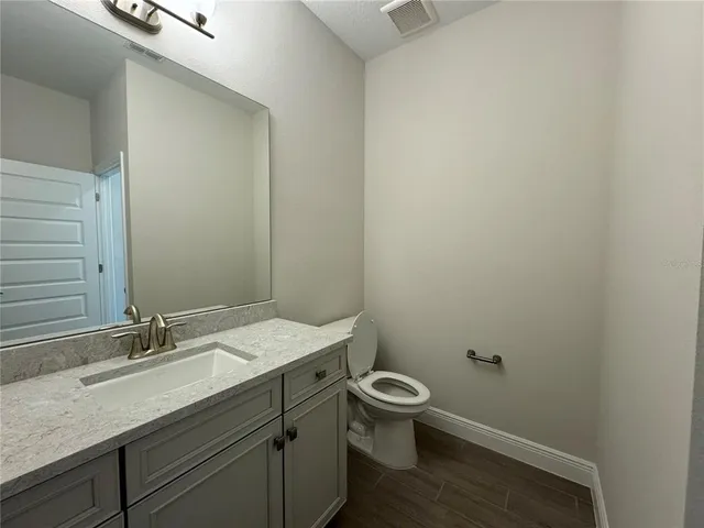 a bathroom with a granite countertop sink a toilet and a mirror