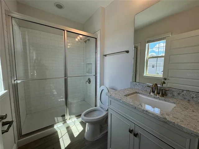 a bathroom with a granite countertop sink toilet a mirror and shower