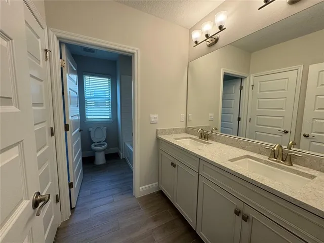 a en suite bathroom with a double vanity sink a mirror and a toilet