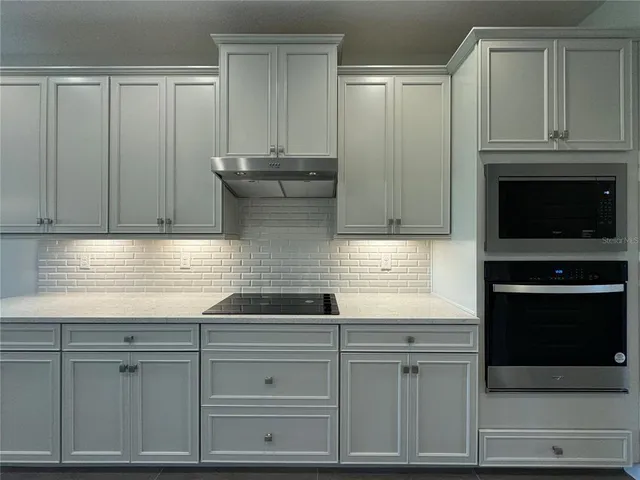 a kitchen with stainless steel appliances granite countertop white cabinets and a stove