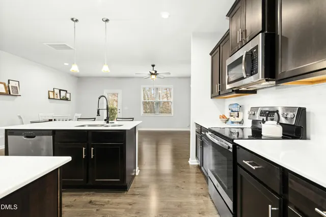 a kitchen with stainless steel appliances granite countertop a sink and stove top oven with wooden floor