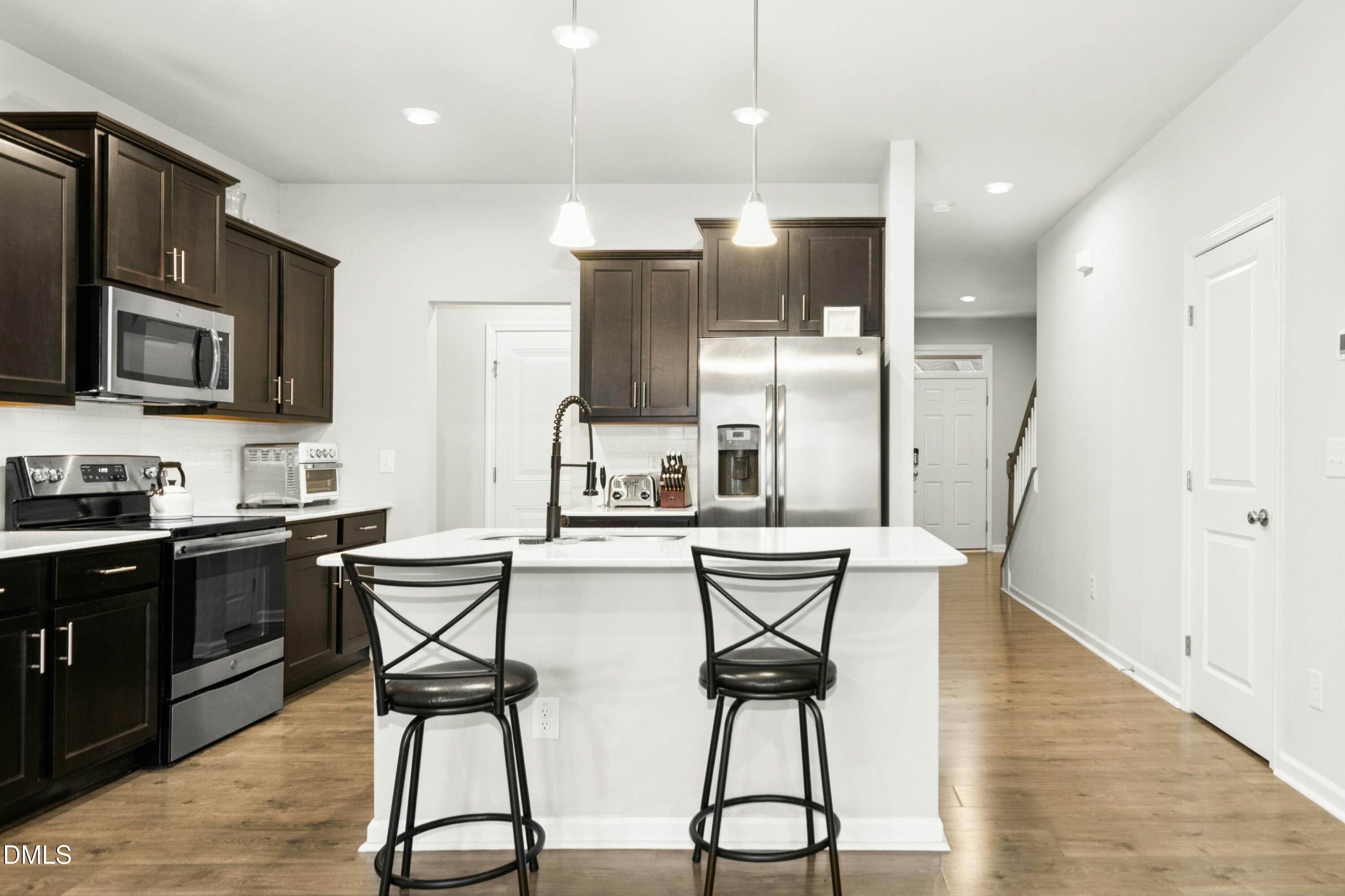 3645 Water Mist Lane Raleigh, NC 27604 - Photo 5 of 29 a kitchen with stainless steel appliances kitchen island granite countertop a refrigerator a stove a sink dishwasher and white cabinets with wooden floor