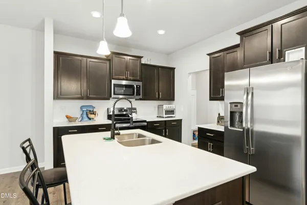 a kitchen with kitchen island a counter top space cabinets stainless steel appliances and wooden floor