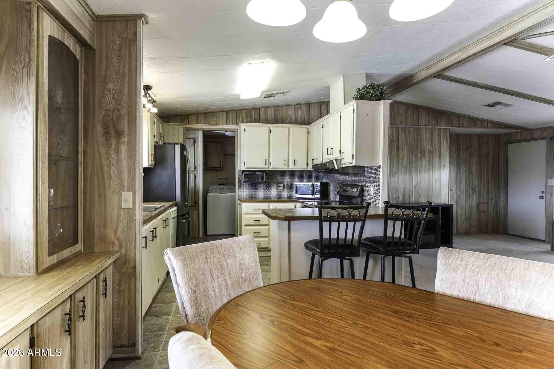 2100 North Trekell Road, Unit 143 Casa Grande, AZ 85122 - Photo 10 of 34 a kitchen with stainless steel appliances kitchen island granite countertop a dining table chairs and a refrigerator