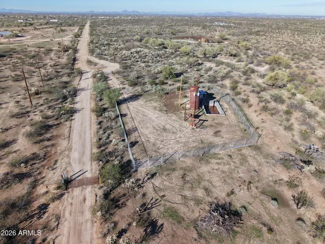 a view of a dry field with trees in the background