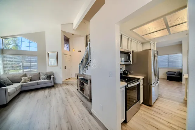 a kitchen with a sink dishwasher a stove and white cabinets with wooden floor
