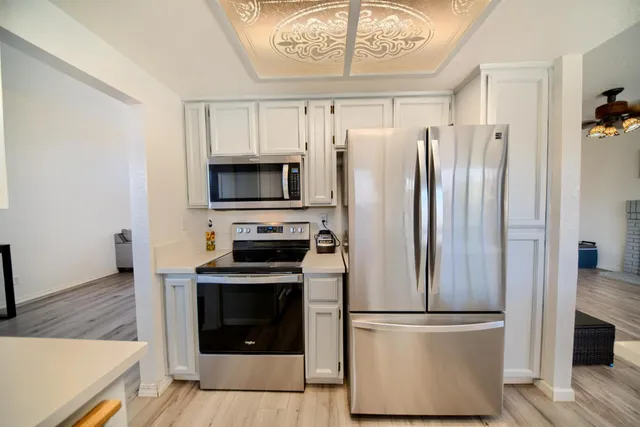 a open kitchen with white cabinets and wooden floor