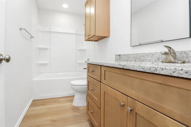 a bathroom with a granite countertop sink a toilet and shower