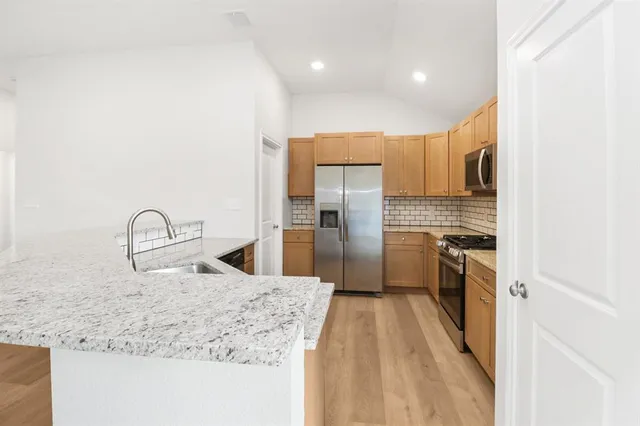 a kitchen with stainless steel appliances granite countertop a refrigerator and a sink