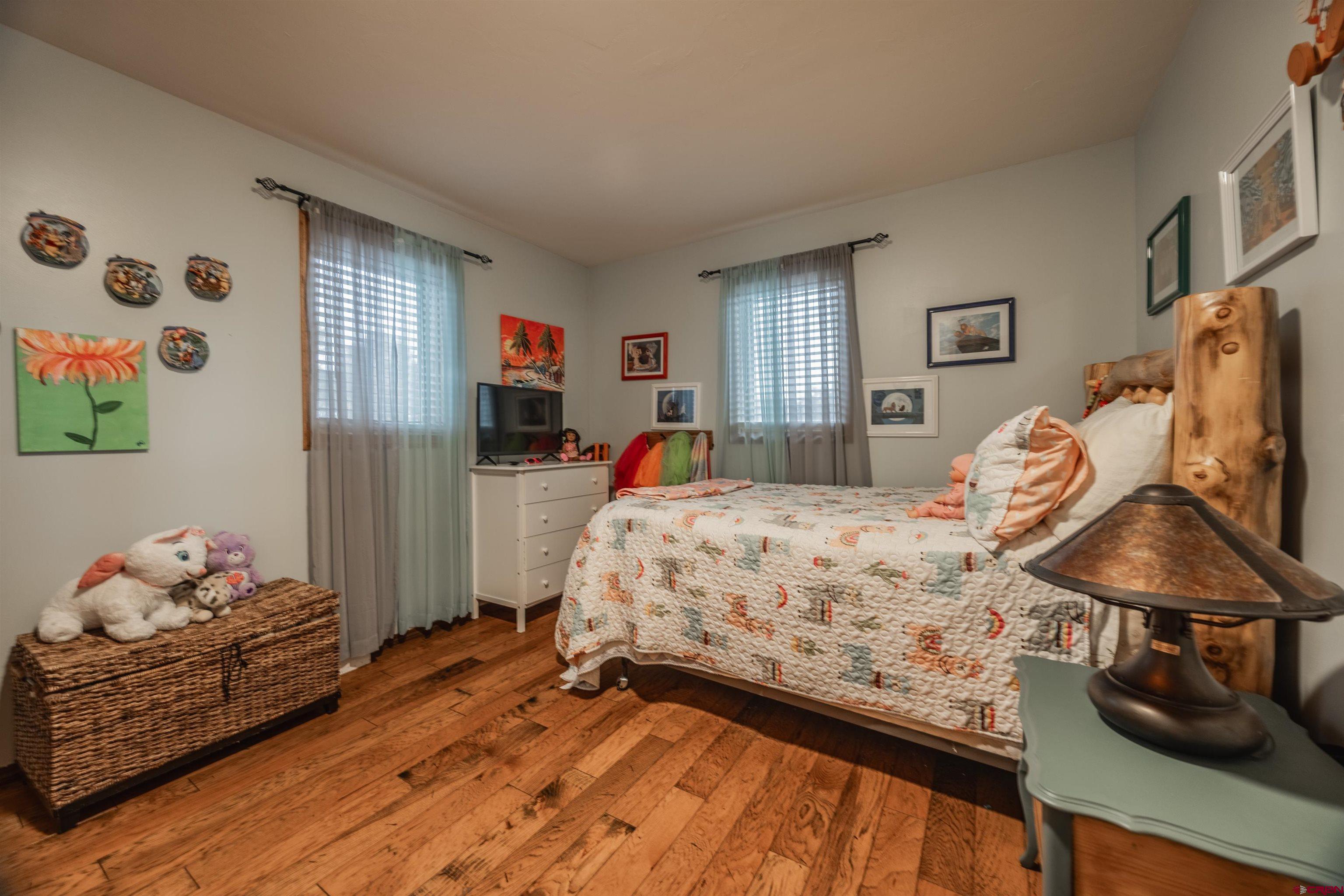 21186 Uintah Road Cedaredge, CO 81413 - Photo 20 of 45 a bedroom with a bed and wooden floor