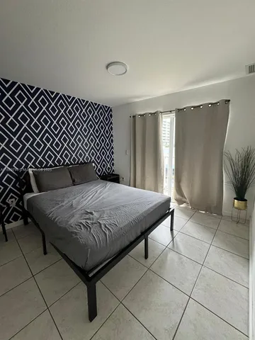 a bed sitting in a bedroom next to a window and a bathroom