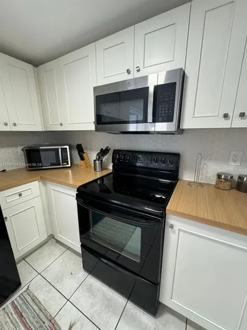 a kitchen with white cabinets and black appliances