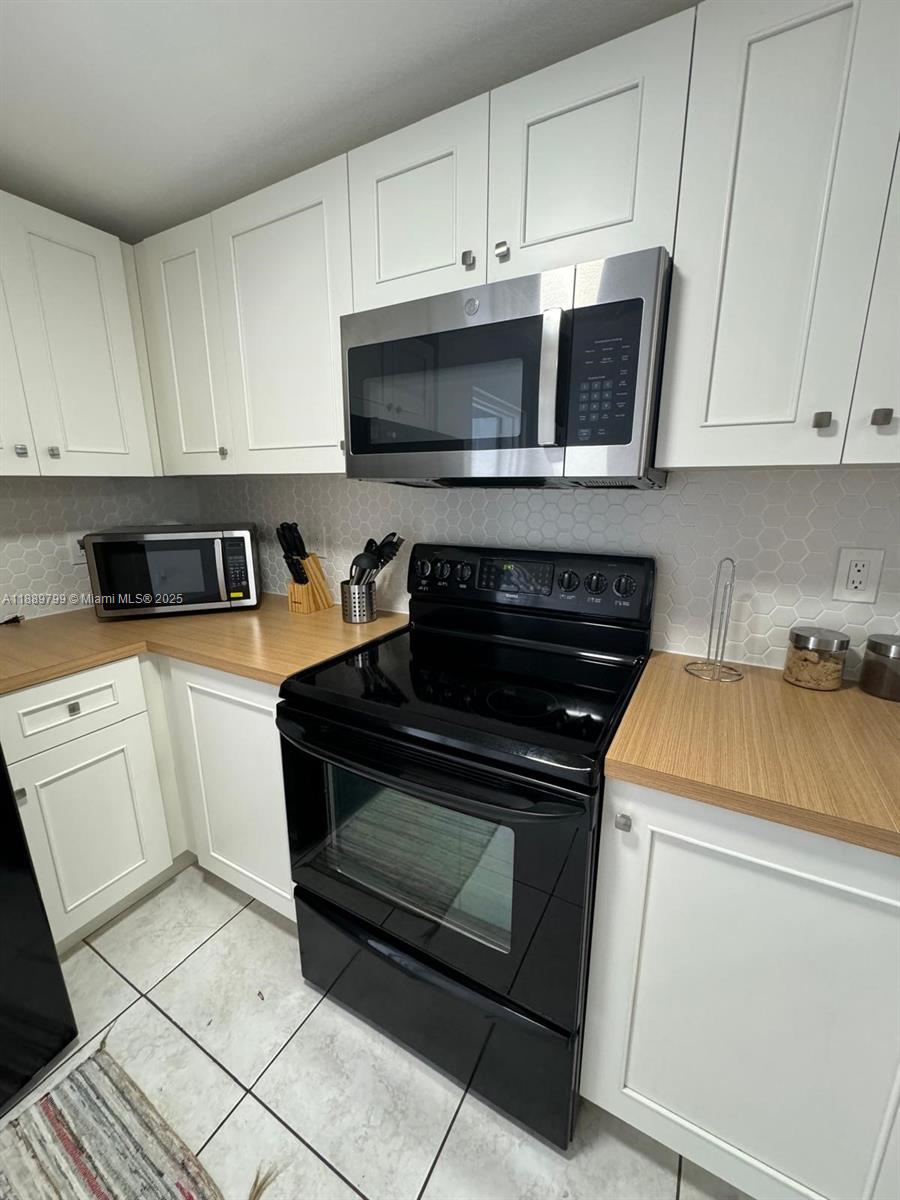 328 Northwest 12th Avenue, Unit 8 Miami, FL 33128 - Photo 6 of 15 a kitchen with white cabinets and black appliances
