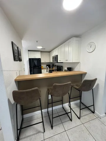 a kitchen with stainless steel appliances kitchen island a table chairs in it and wooden floors