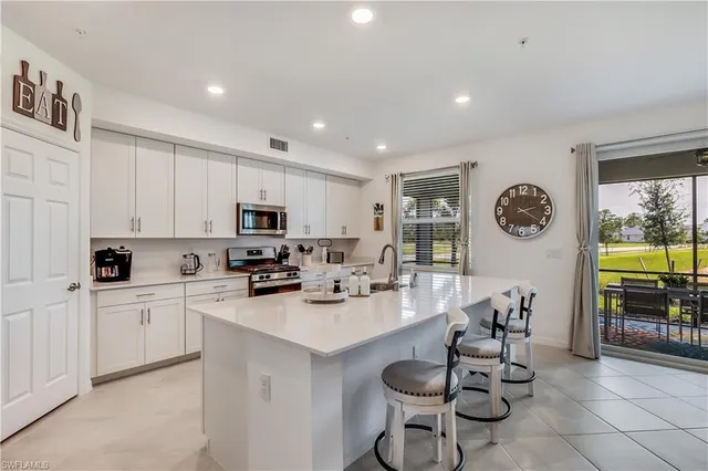 a kitchen with stainless steel appliances granite countertop a stove top oven a sink a dining table and chairs with white cabinets