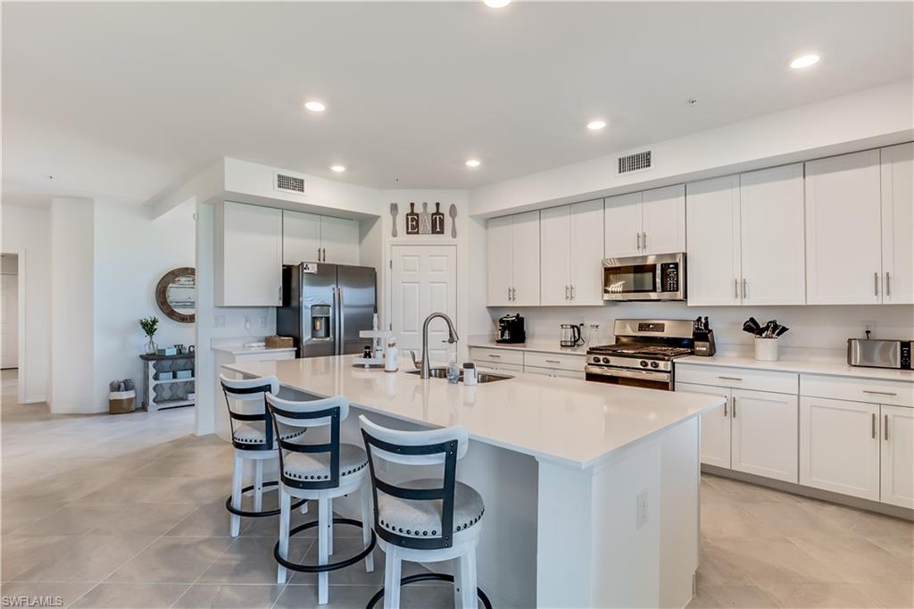 43330 Water Bird Way, Unit 6911 Punta Gorda, FL 33982 - Photo 7 of 17 Kitchen with an island with sink, sink, white cabinetry, and appliances with stainless steel finishes