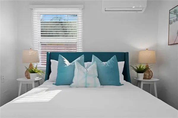 a bedroom with a bed a painting on the wall and a window