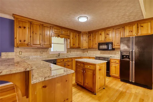 a kitchen with stainless steel appliances granite countertop a stove a sink dishwasher a refrigerator and cabinets with wooden floor