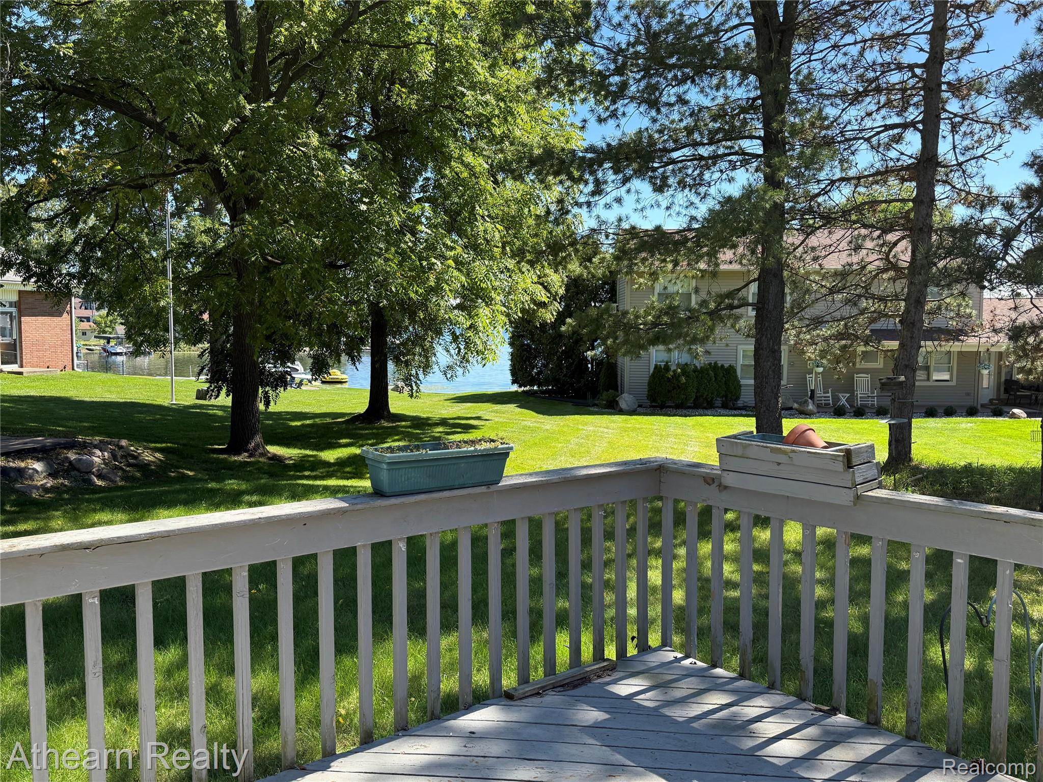 11449 Torrey Road Fenton, MI 48430 - Photo 4 of 30 Outdoor deck with painted wood railing overlooking a manicured lawn and mature trees