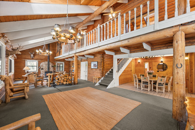 4725 Pine Ridge Road Evanston, UT 82930 - Photo 7 of 82 Vaulted ceilings with exposed wood beams, a prominent stone-clad fireplace, and a second-story loft with a white spindle railing