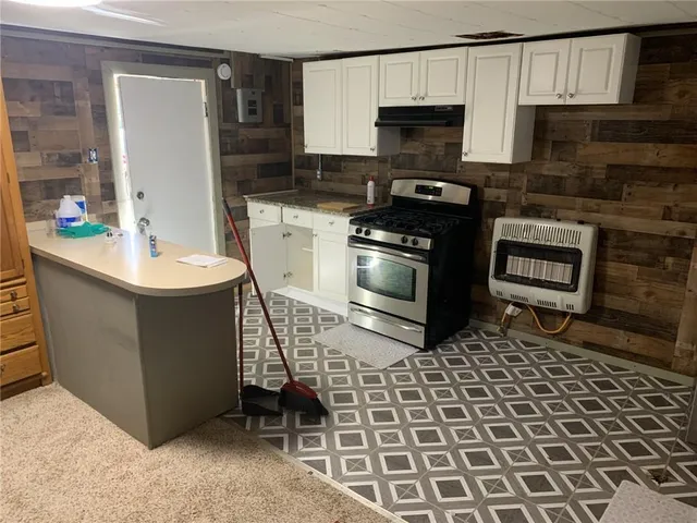 a kitchen with stainless steel appliances granite countertop a refrigerator a stove and a sink with wooden floors