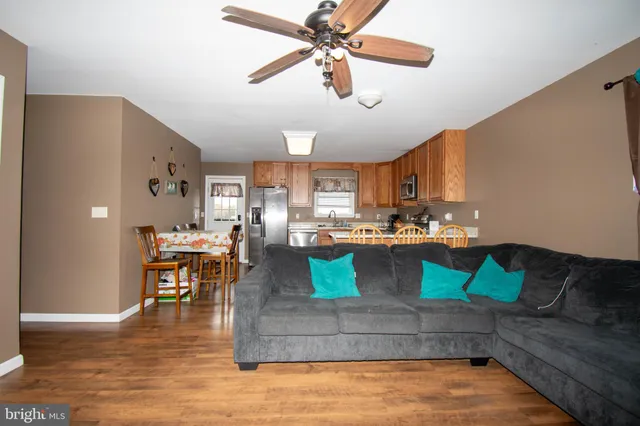 a kitchen with stainless steel appliances granite countertop a refrigerator a stove top oven a dining table and chairs with wooden floor