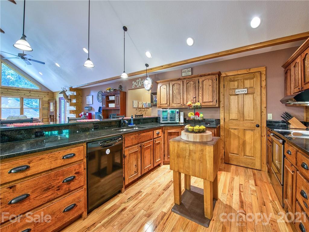273 Mellow Springs Road Waynesville, NC 28786 - Photo 13 of 40 a kitchen with stainless steel appliances granite countertop wooden cabinets a stove top oven a sink and dishwasher a oven with wooden floor