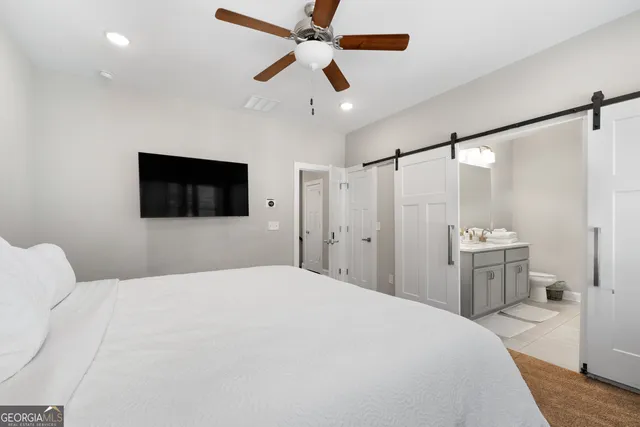 a bedroom with a large bed and a flat tv screen